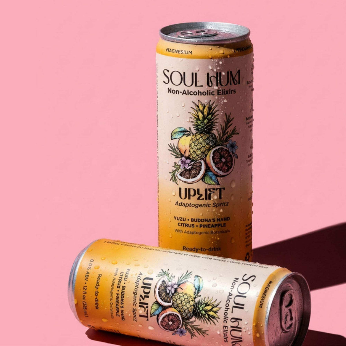 Uplift Adaptogenic Spritz non-alcoholic drink cans in peach and orange, featuring tropical fruit illustrations and pull tabs