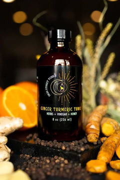 Ginger Turmeric Tonic in a glass mug with fresh ginger and turmeric roots nearby