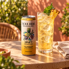 Uplift Adaptogenic Spritz can beside a spritz over ice on a sunlit cafe table